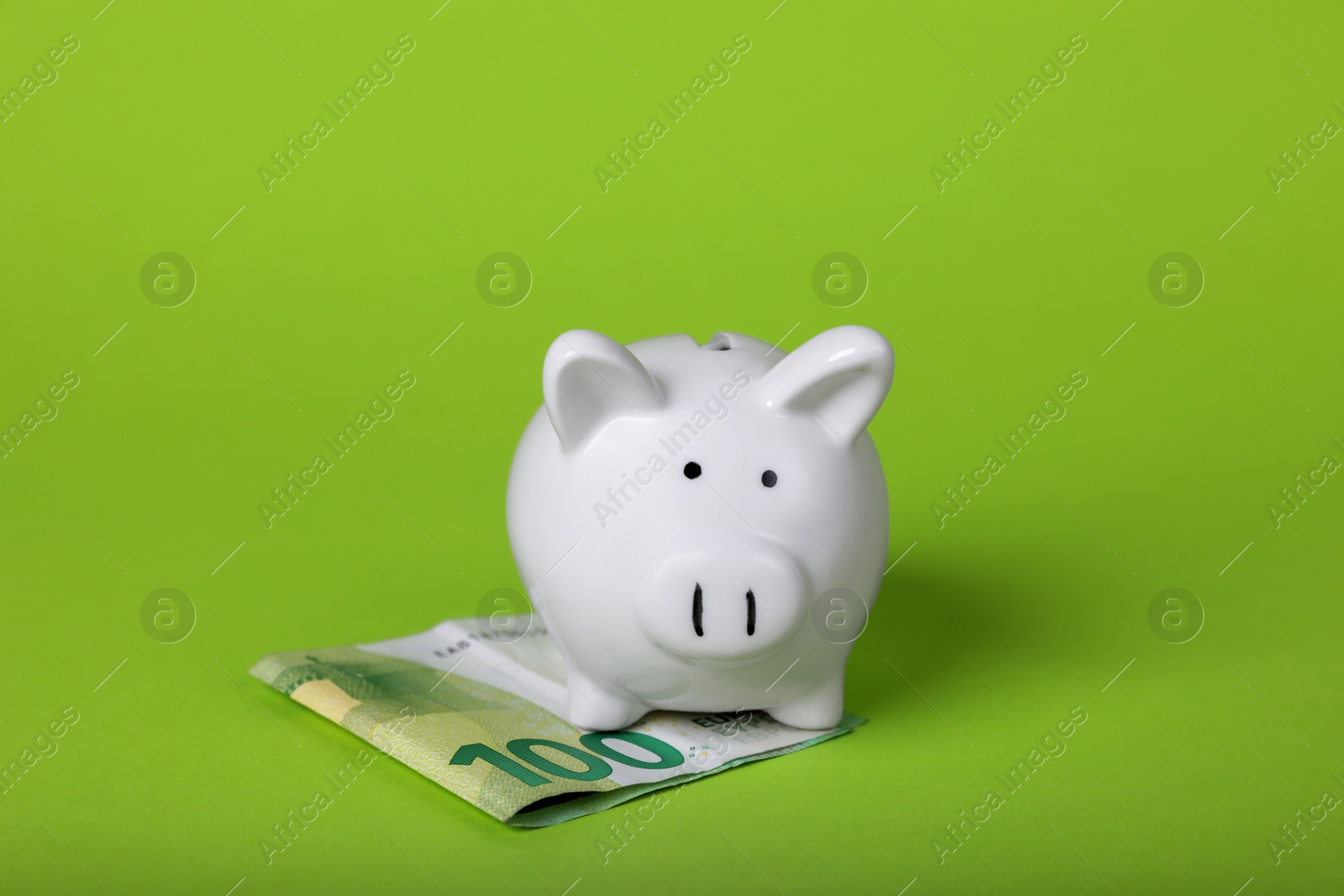 Photo of Ceramic piggy bank and euro banknote on light green background. Financial savings