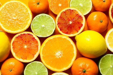 Different citrus fruits on color background, top view