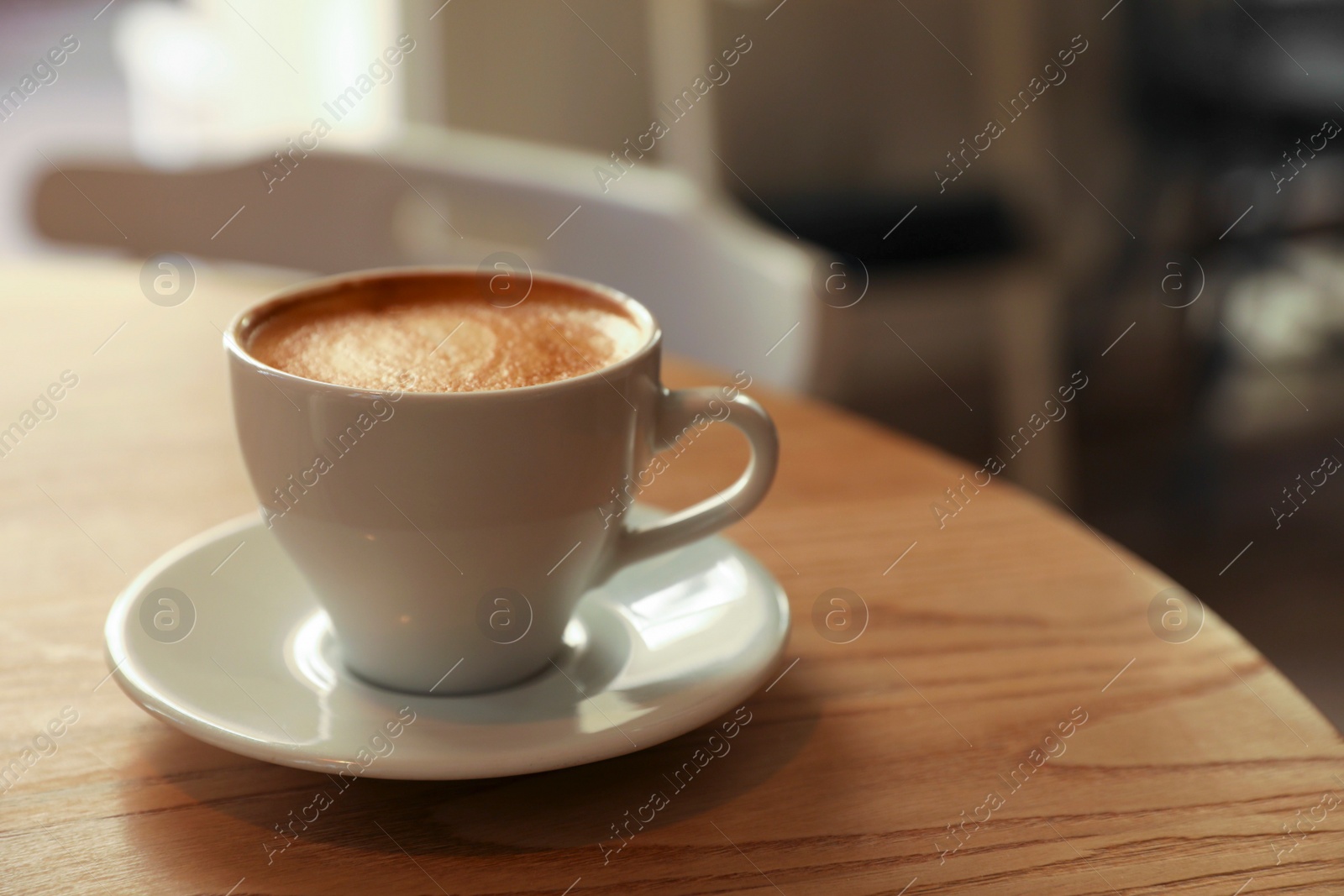 Photo of Cup of aromatic hot coffee on wooden table in cafe