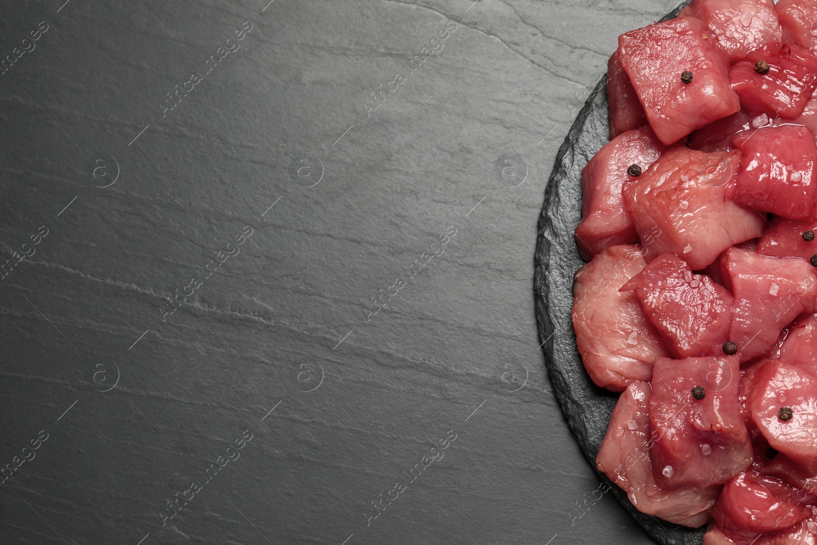 Photo of Cooking delicious goulash. Raw beef meat with spices on black table, top view and space for text