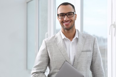 Photo of Smiling young businessman with laptop in modern office