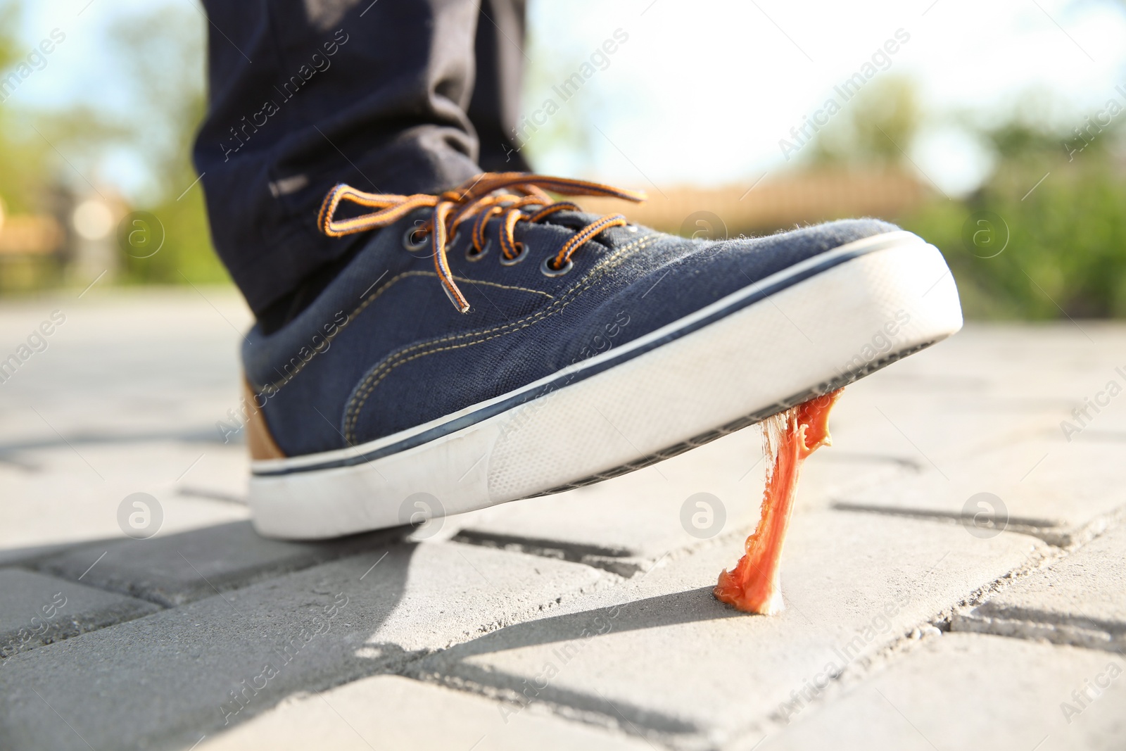 Photo of Man stepping in chewing gum on sidewalk. Concept of stickiness