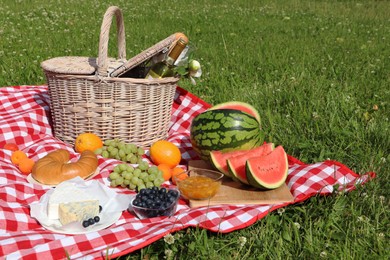 Picnic blanket with delicious food and wine outdoors on summer day