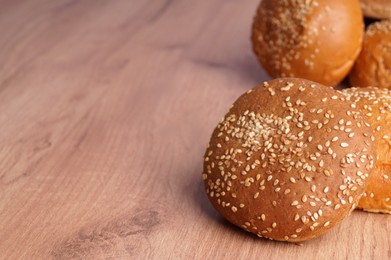 Photo of Fresh buns with sesame seeds on wooden table. Space for text