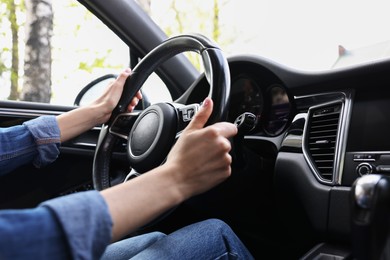 Photo of Woman holding steering wheel while driving her car, closeup