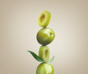 Cut and whole olives with leaf on dusty beige background