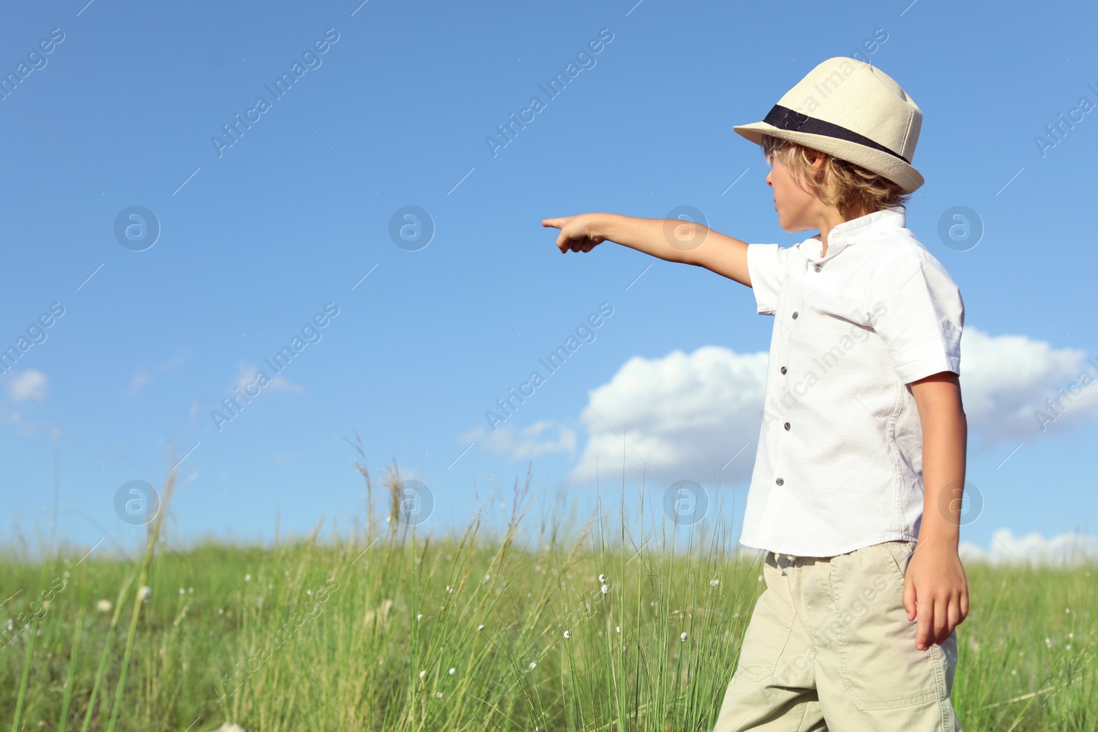 Photo of Cute little boy wearing stylish hat outdoors, space for text. Child spending time in nature