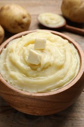 Photo of Bowl of delicious mashed potato with butter on wooden table, closeup