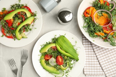 Photo of Delicious vegetable salads with avocado and microgreen served on light table, flat lay