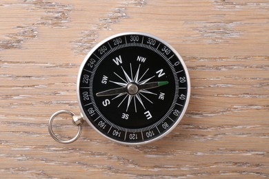 Photo of One compass on wooden table, top view. Tourist equipment