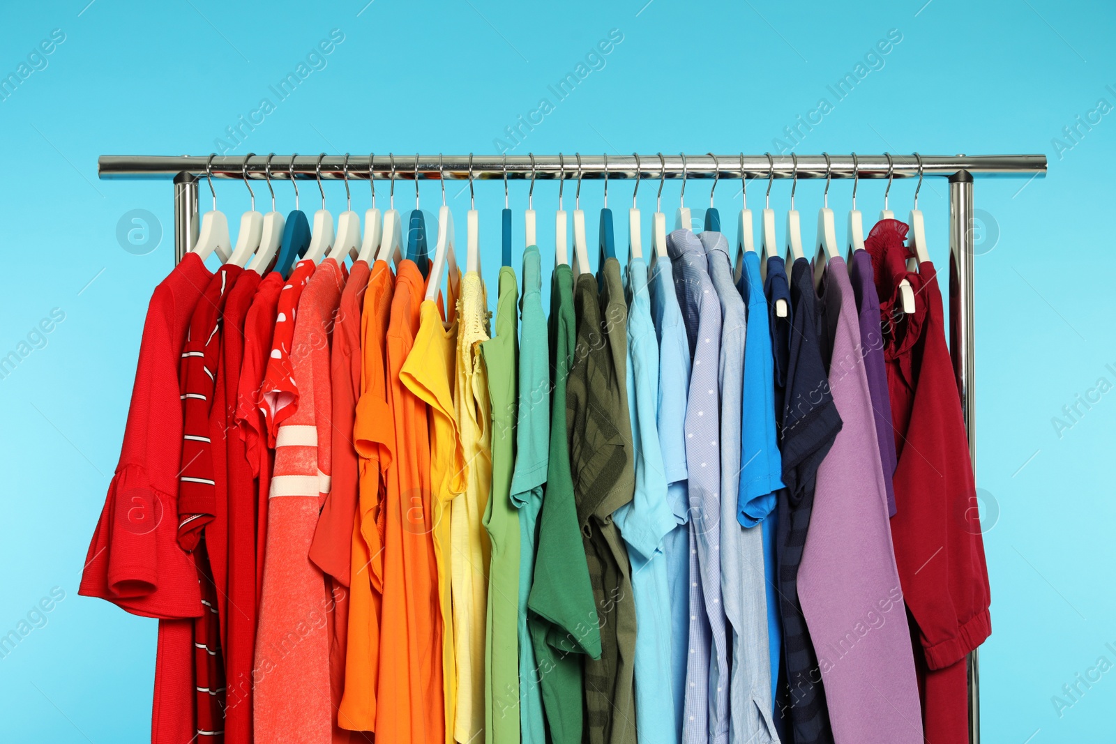 Photo of Wardrobe rack with different bright clothes on color background