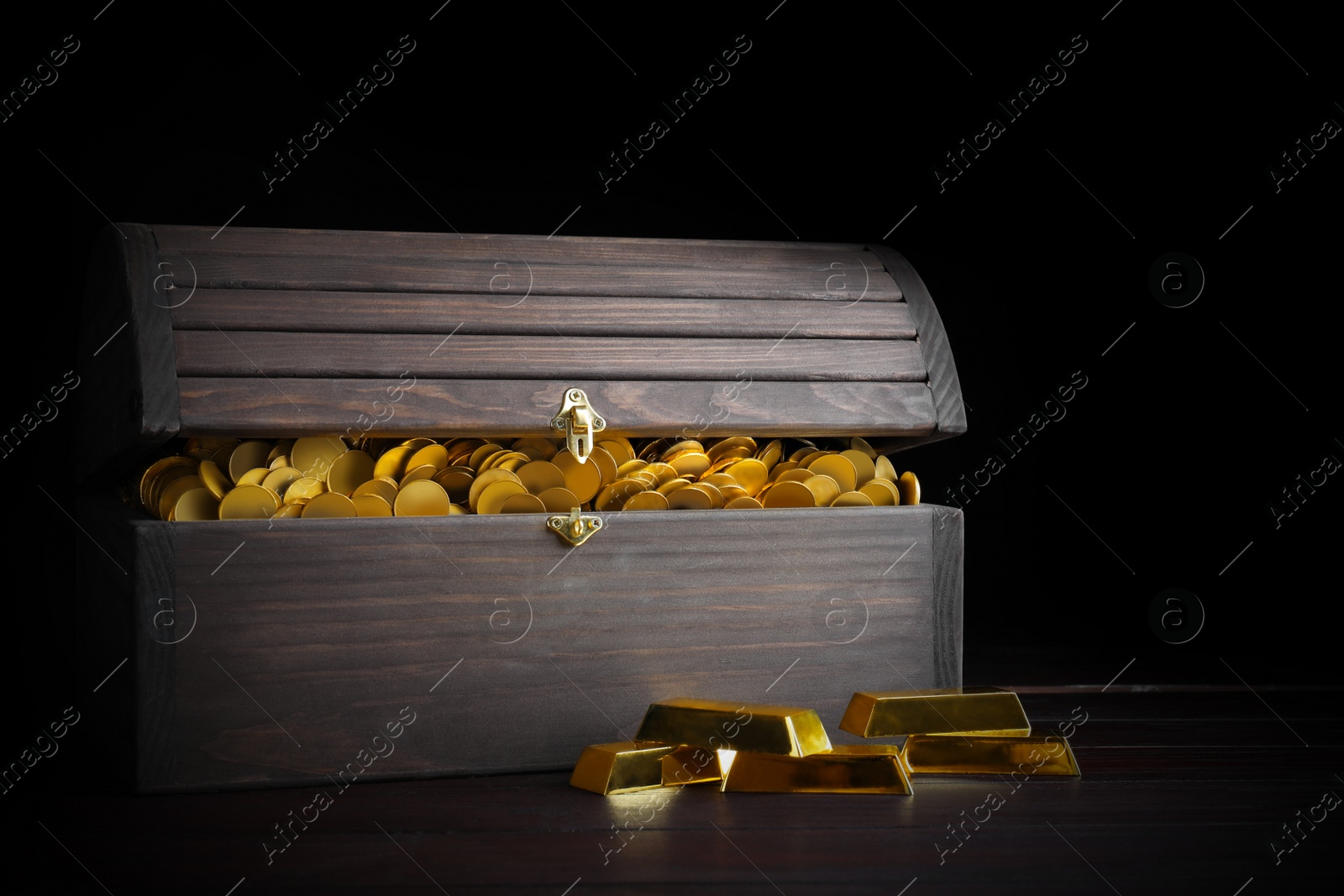 Image of Open treasure chest with coins and gold bars on wooden table