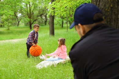 Photo of Suspicious adult man spying on kids at park. Child in danger