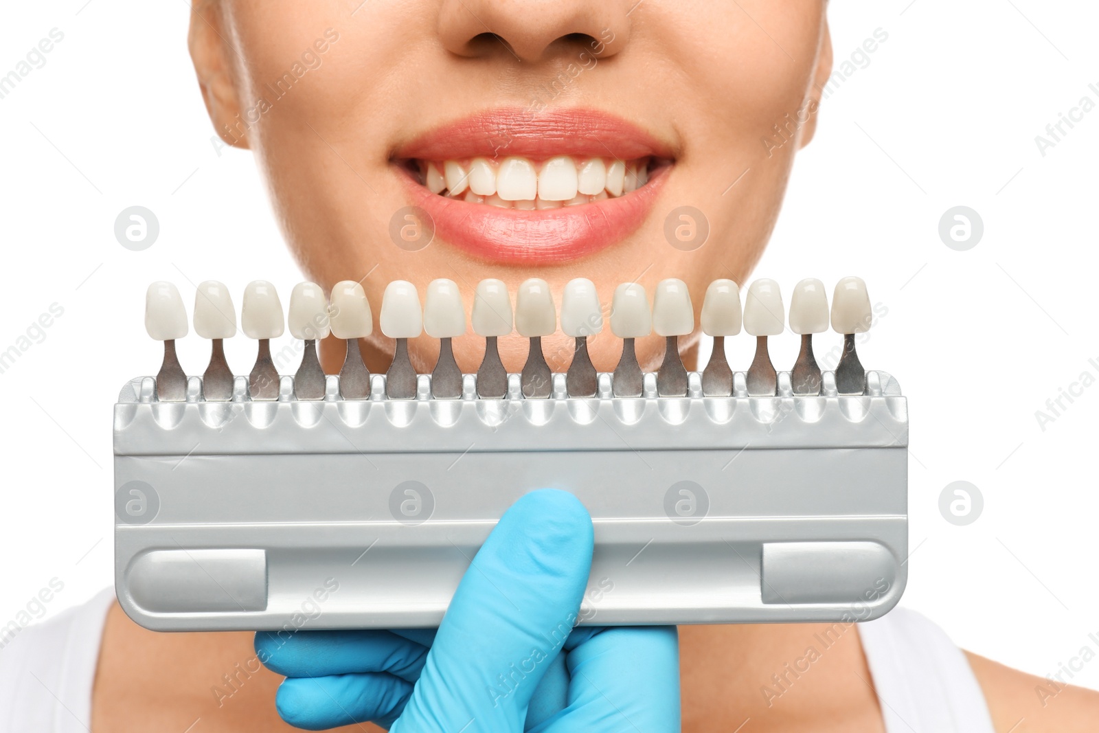 Photo of Doctor checking young woman's teeth color on white background, closeup. Cosmetic dentistry