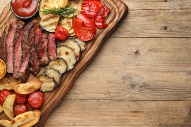 Delicious grilled beef with vegetables, spices and tomato sauce on wooden table, top view. Space for text