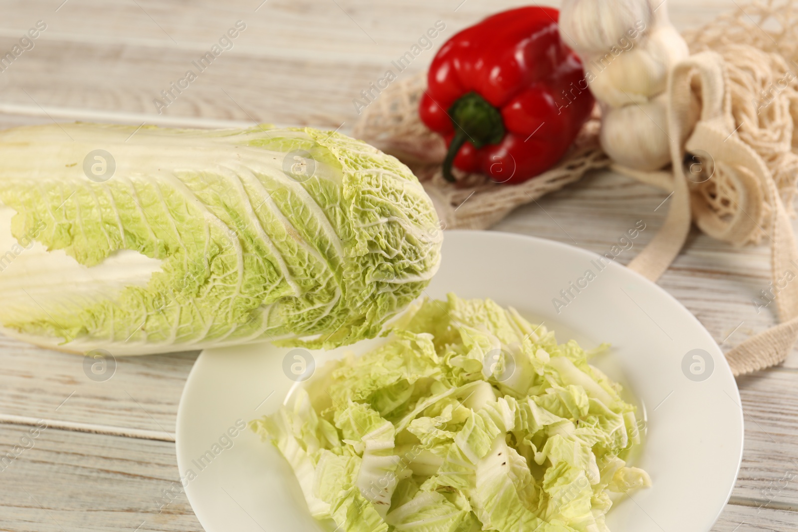 Photo of Fresh Chinese cabbage, bell pepper and garlic on wooden table, closeup