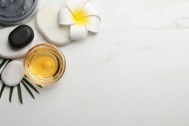 Photo of Flat lay composition with spa stones, plumeria flower and bowl of massage oil on white marble table. Space for text