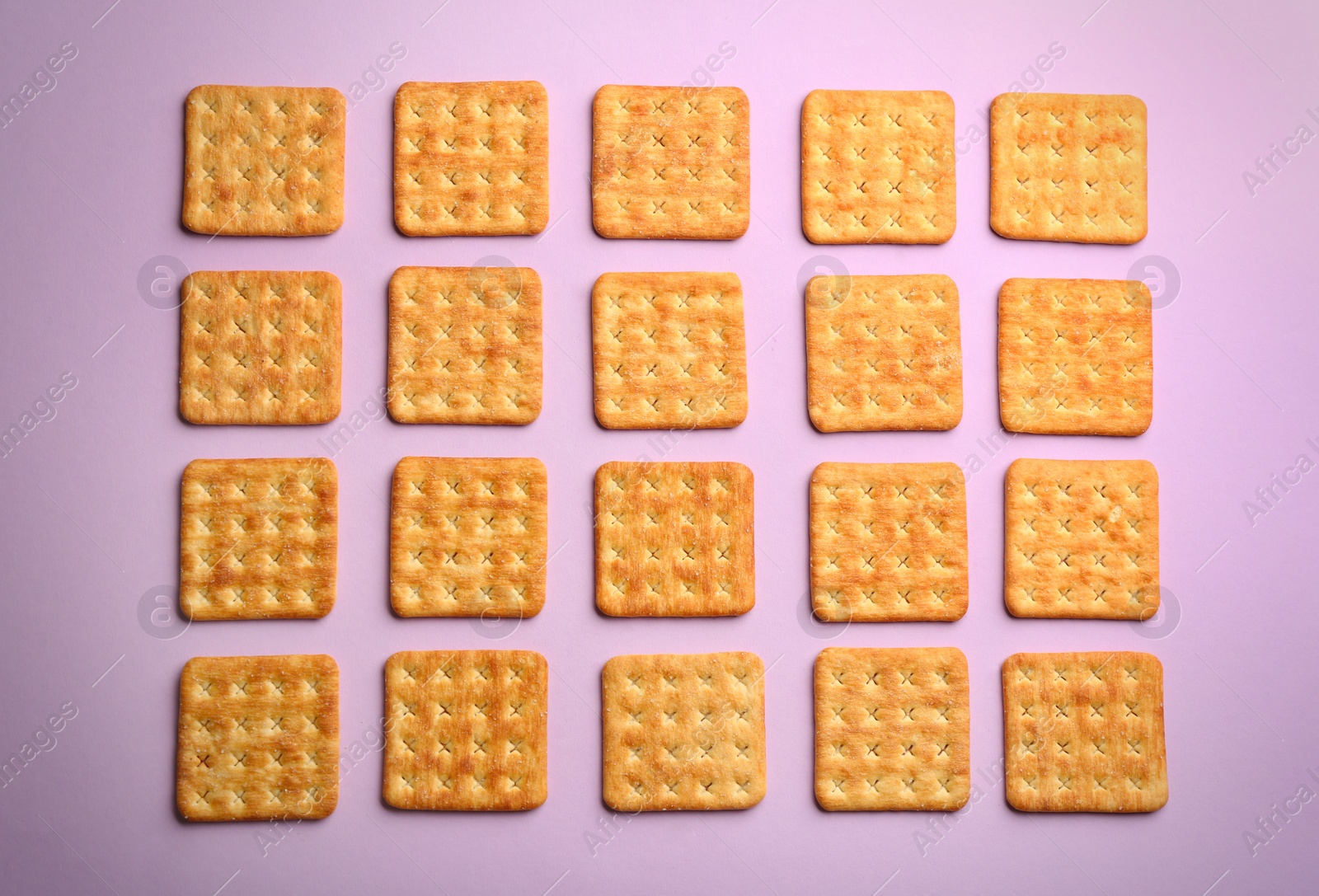 Photo of Delicious crackers on violet background, flat lay