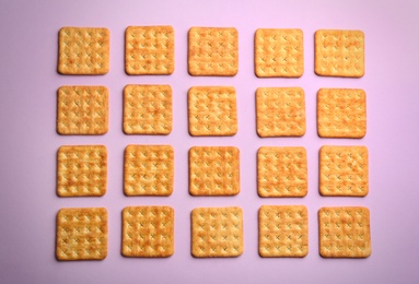 Delicious crackers on violet background, flat lay