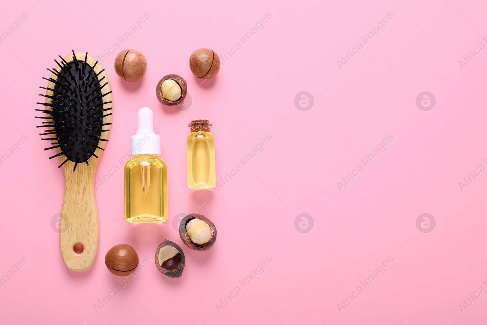 Photo of Delicious organic Macadamia nuts, natural oil and brush on pink background, flat lay. Space for text