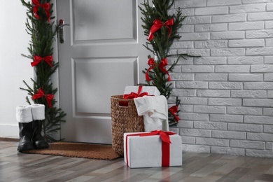 Stylish hallway interior with decorated door and Christmas gifts, space for text