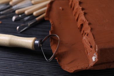 Clay and loop tool on dark gray wooden table, closeup