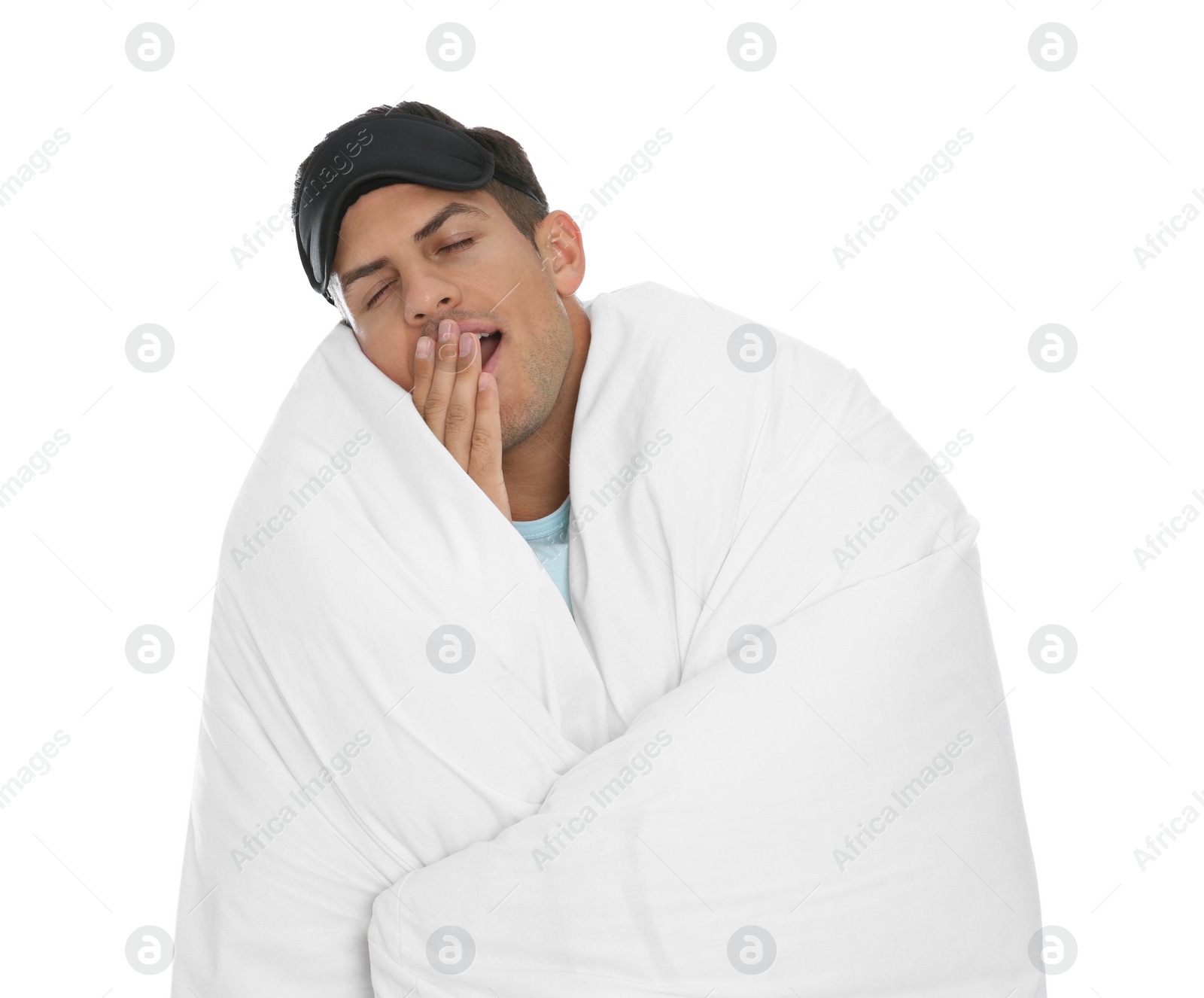 Photo of Man in sleeping mask wrapped with blanket yawning on white background