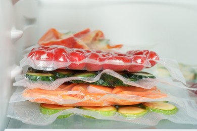 Photo of Vacuum bags with different vegetables in fridge, closeup. Food storage