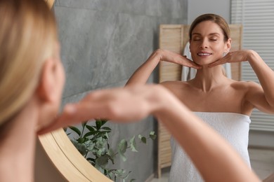 Woman massaging her face near mirror in bathroom