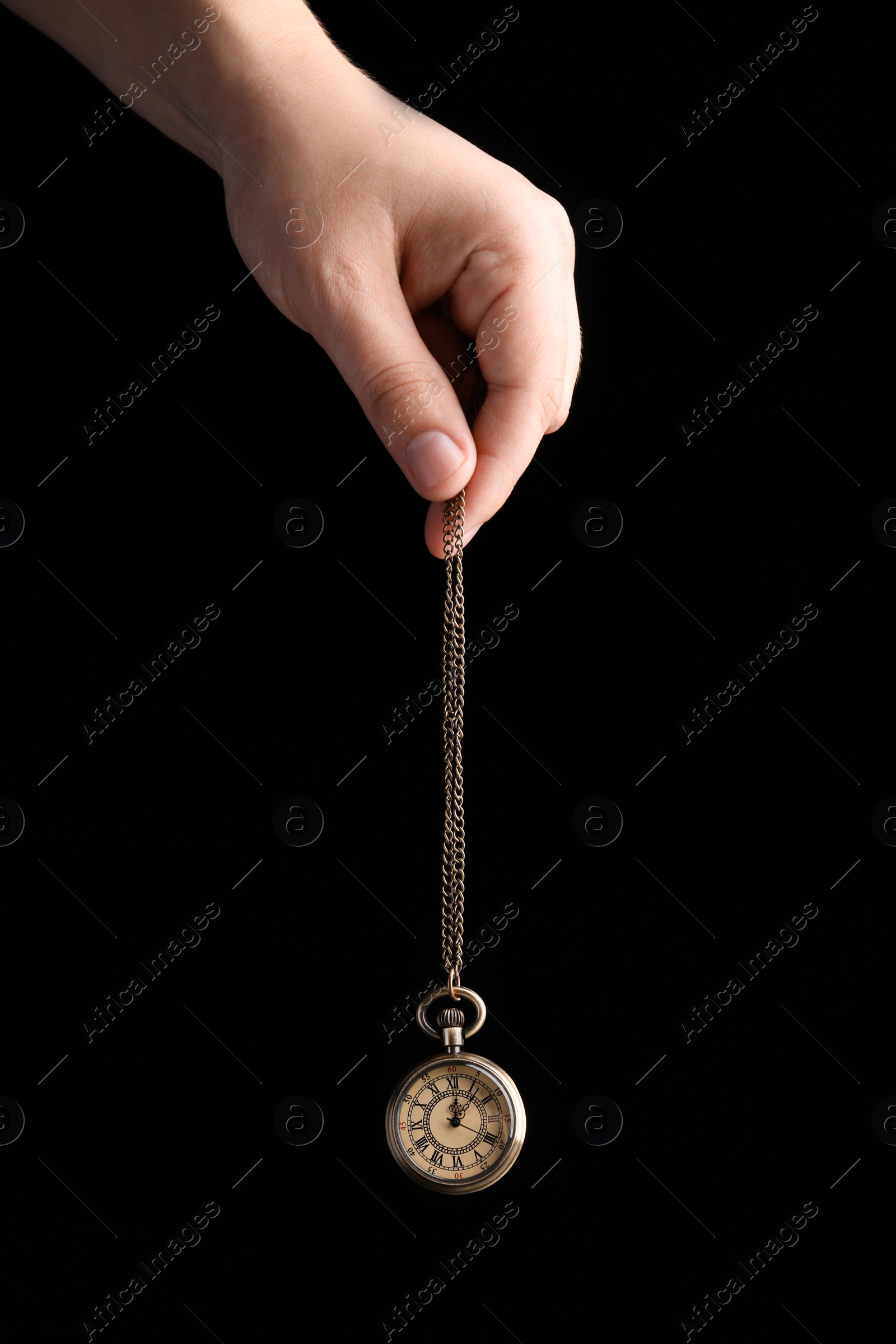 Photo of Psychotherapist with pendulum on black background, closeup. Hypnotherapy session