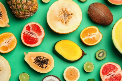 Photo of Flat lay composition with tasty melon and fresh tropical fruits on green background