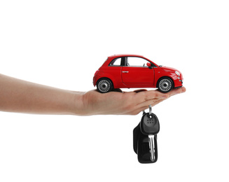 Woman holding key and miniature automobile model on white background, closeup. Car buying
