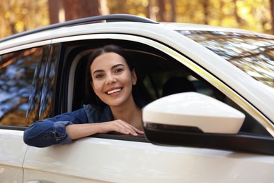 Photo of Happy young woman looking out of car window, view from outside. Enjoying trip