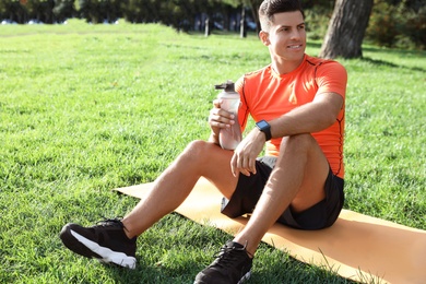 Man with fitness tracker and bottle of water after training in park