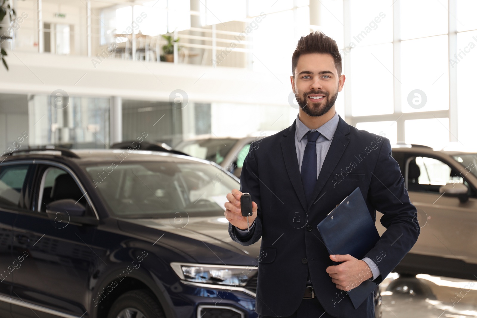 Photo of Salesman with key and clipboard in car salon