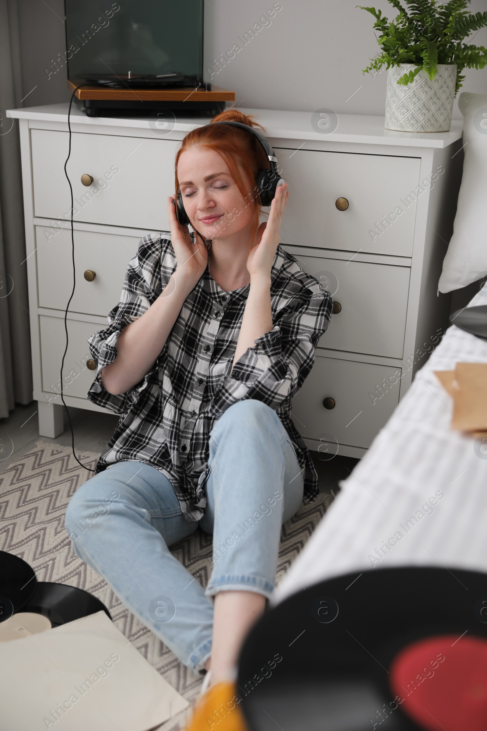 Photo of Young woman listening to music with turntable in bedroom