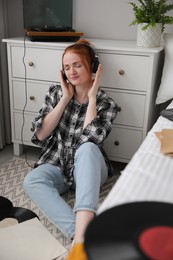 Young woman listening to music with turntable in bedroom