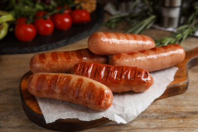 Photo of Delicious grilled sausages served on wooden table