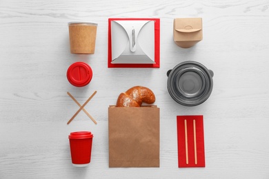 Flat lay composition with paper bag and different takeaway items on wooden background. Space for design