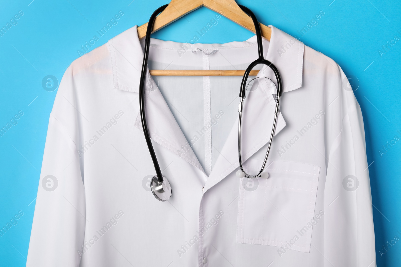 Photo of Medical uniform and stethoscope on light blue background