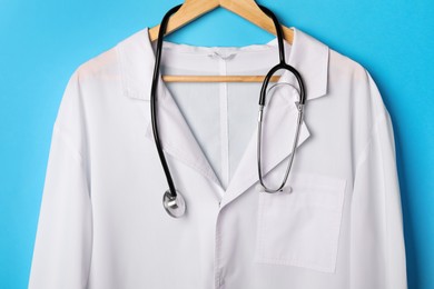 Photo of Medical uniform and stethoscope on light blue background