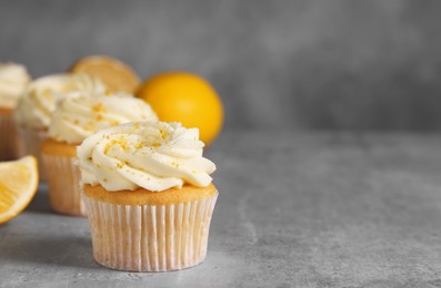 Photo of Delicious cupcakes with white cream and lemon zest on gray table, closeup. Space for text