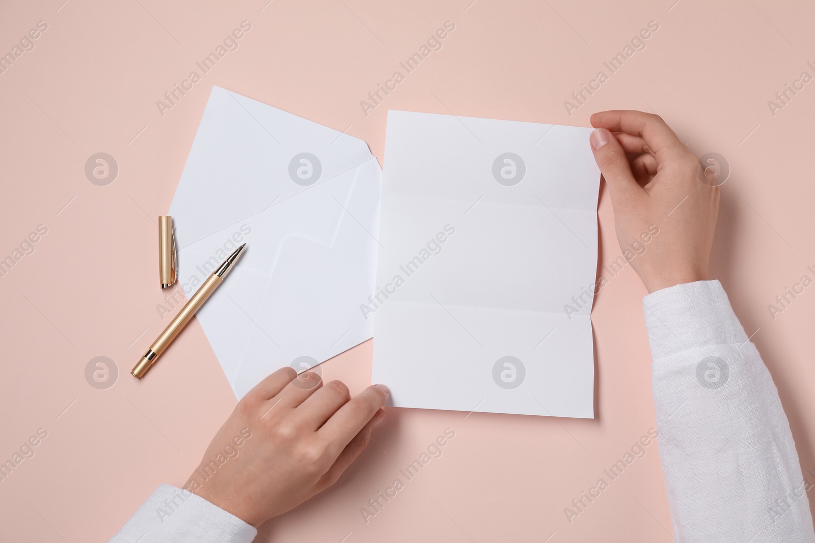 Photo of Woman with blank paper sheet at beige table, top view. Space for text