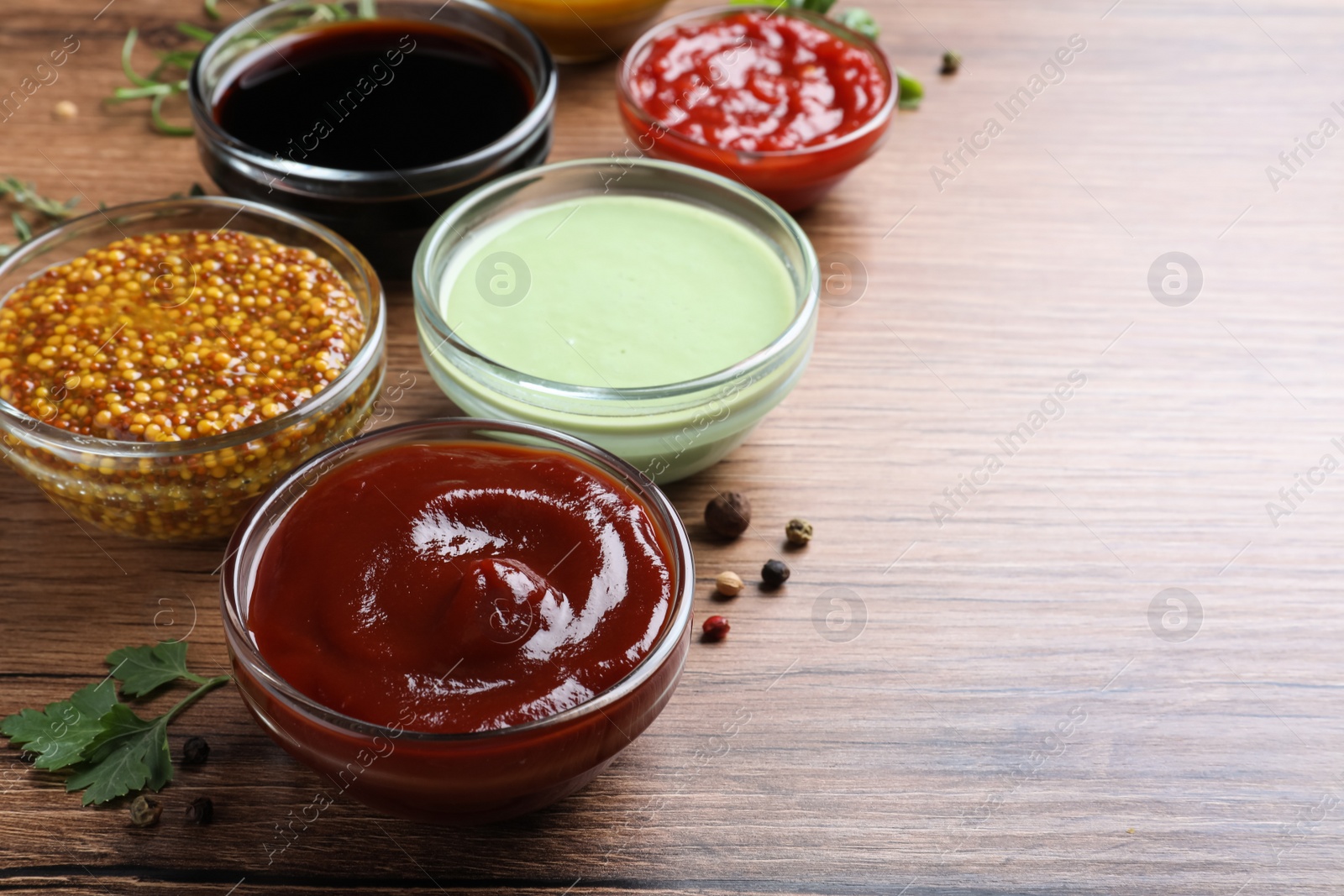 Photo of Many different sauces on wooden table, space for text