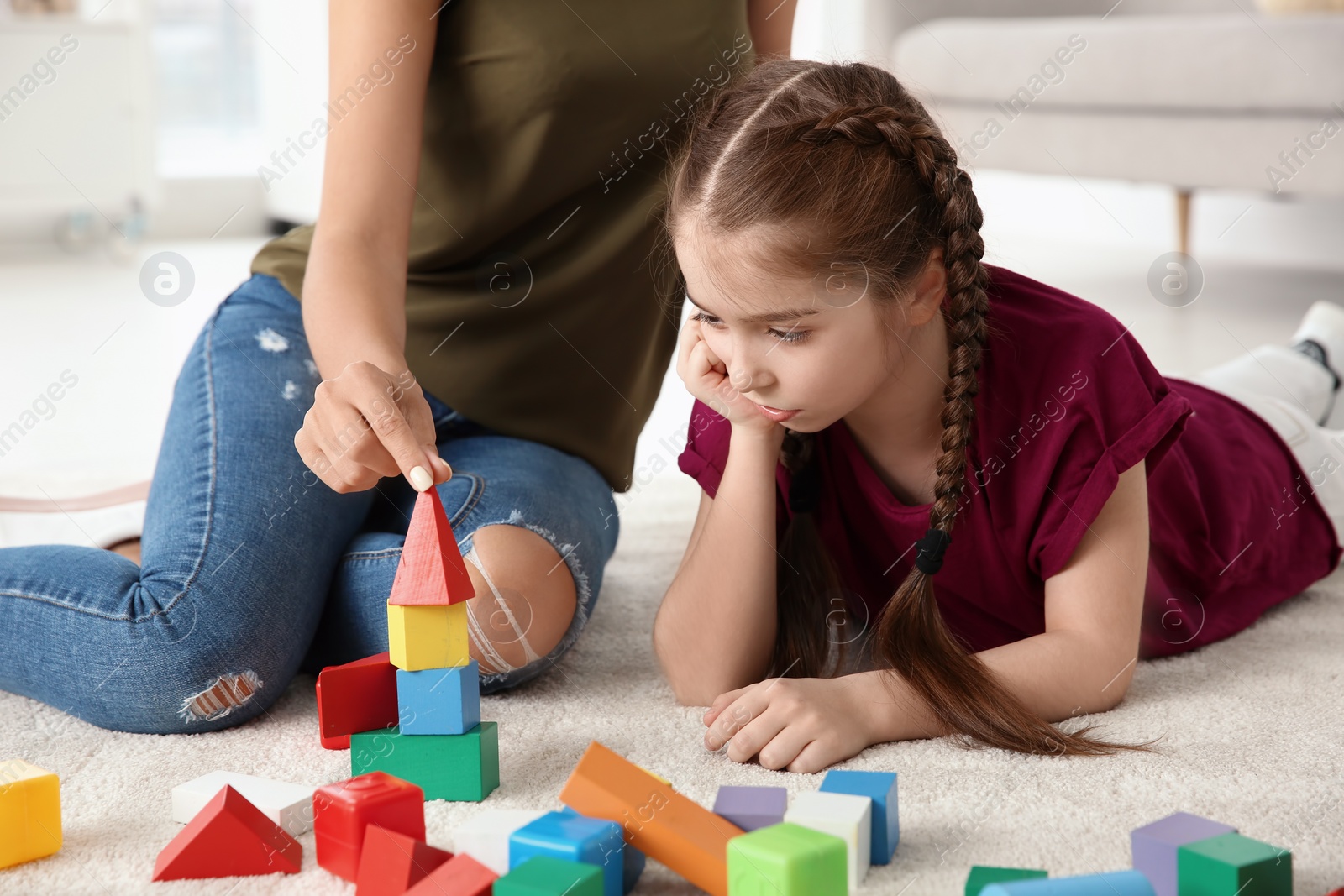 Photo of Young woman and little girl with autistic disorder playing at home