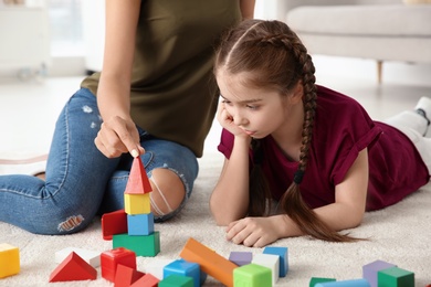 Young woman and little girl with autistic disorder playing at home