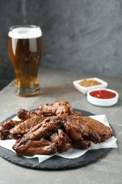 Photo of Delicious chicken wings served with beer on grey table