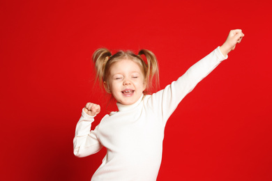 Portrait of cute little girl on red background