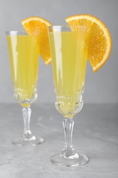 Photo of Glasses of Mimosa cocktail with garnish on marble table