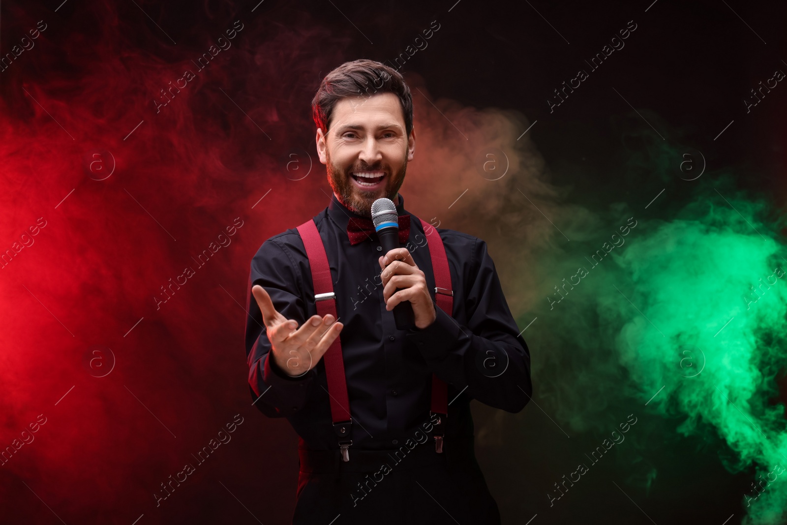 Photo of Emotional man with microphone singing in color lights